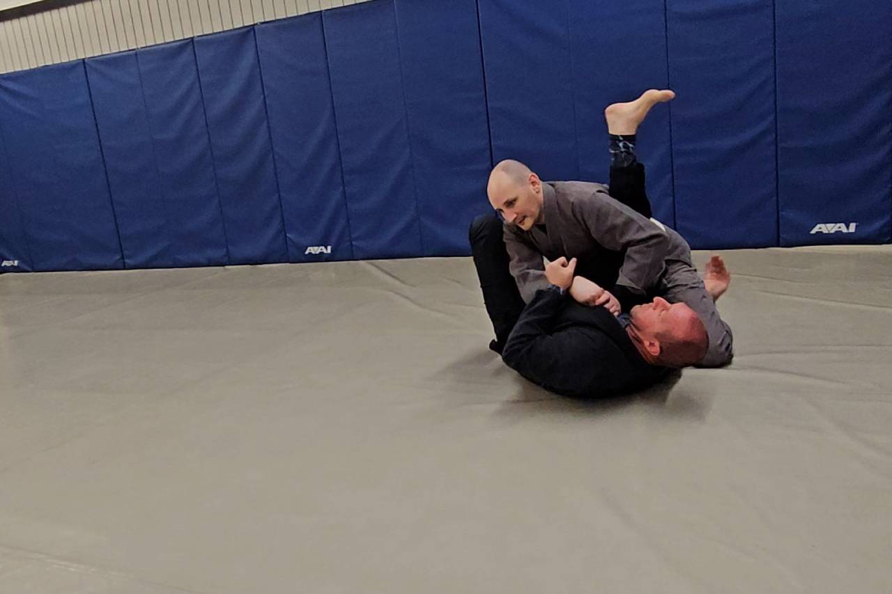 Two individuals practicing Brazilian Jiu-Jitsu on a mat.